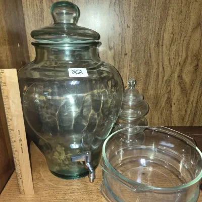 Sale Photo Thumbnail #36: Large green glass drink dispenser with a chrome spigot and lid, displayed alongside clear glass serving bowls and a tiered jar.