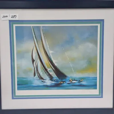 Sale Photo Thumbnail #504: Framed nautical art print depicting a racing sailboat on choppy water, presented with layered blue and teal matting in a dark blue frame.