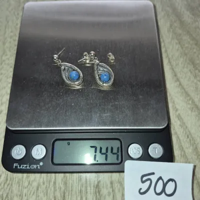 Sale Photo Thumbnail #861: Pair of sterling silver dangle earrings set with round lapis lazuli stones, displayed on a digital scale weighing 7.44 grams.