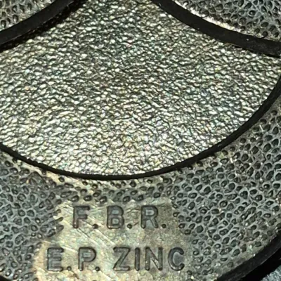 Sale Photo Thumbnail #663: Close-up of a maker's mark stamped 'F.B.R. E.P. ZINC' on a textured metal object.
