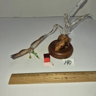 Sale Photo Thumbnail #234: Hand-blown glass figurine depicting a duck in flight near cattails, mounted on a burl wood and wooden base, displayed alongside miniature glass figures.