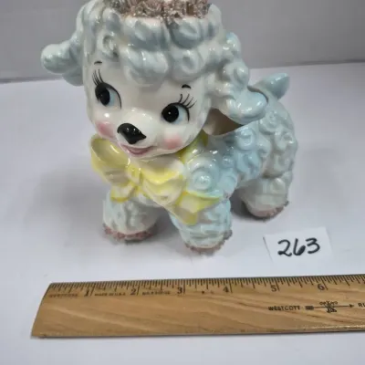 Sale Photo Thumbnail #447: Vintage mid-century ceramic lamb planter featuring pastel blue shading, a yellow bow, and spaghetti porcelain details around the head.