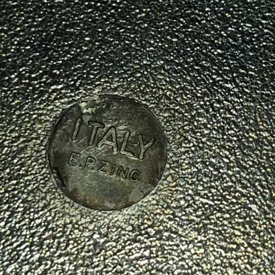Sale Photo Thumbnail #665: Close-up detail of a maker's mark reading "ITALY E.P. ZINC" stamped on a textured metal surface.