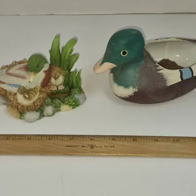 Sale Photo Thumbnail #328: Two duck decor pieces, including a small resin figurine featuring a mallard family in a nest and a vintage ceramic mallard planter.