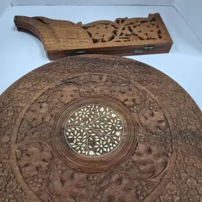 Sale Photo Thumbnail #300: Hand-carved Anglo-Indian folding side table featuring intricate floral wood carvings and a central brass or bone inlay motif on the circular tabletop.