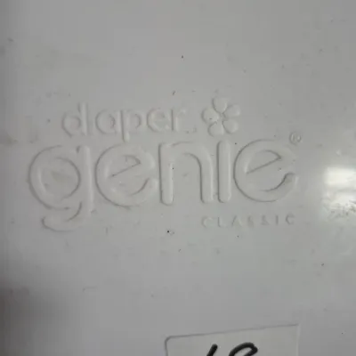 Sale Photo Thumbnail #103: Close-up detail of a white Diaper Genie Classic pail lid, featuring embossed branding and an auction tag marked with the number 68.