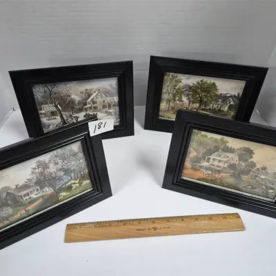 Sale Photo Thumbnail #312: Set of four framed Currier & Ives style seasonal landscape prints in matching black wooden frames, displayed with a wooden ruler for scale.