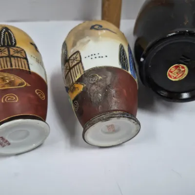 Sale Photo Thumbnail #395: Trio of vintage Japanese miniature vases, including a pair of hand-painted Satsuma-style porcelain pieces and one dark glazed ceramic vase, showing base maker marks.