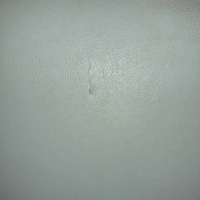 Sale Photo Thumbnail #841: Close-up view of white vinyl upholstery featuring a small vertical tear in the surface material.