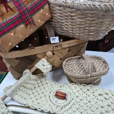 Sale Photo Thumbnail #153: Collection of woven baskets in various sizes and styles, including a plaid-ribbon trimmed basket, a lidded mini basket, and an off-white macrame wall hanging with a wooden bead accent.