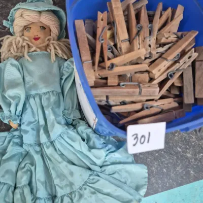 Sale Photo Thumbnail #535: Handmade fabric doll in a light blue dress and matching bonnet next to a blue plastic tub filled with vintage wooden clothespins.