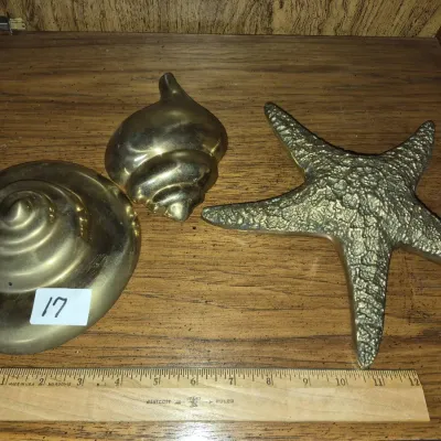 Sale Photo Thumbnail #27: Set of three vintage polished brass nautical decorative items, including a textured starfish and two seashell figurines, shown with a ruler for size reference.