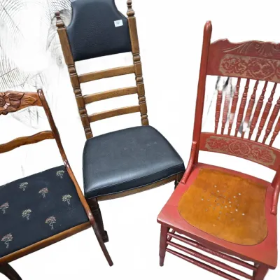 Sale Photo Thumbnail #150: Collection of three vintage wooden side chairs, including a carved rose-back chair with floral upholstery, a oak ladder-back with black vinyl seat, and a painted red spindle-back chair with stenciled details.