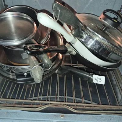 Sale Photo Thumbnail #726: Assorted cookware stack including stainless steel and non-stick pots, pans, and lids inside an oven.