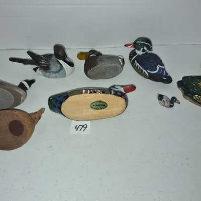 Sale Photo Thumbnail #824: Collection of eight miniature duck decoys and figurines, including carved wooden and hand-painted resin examples.