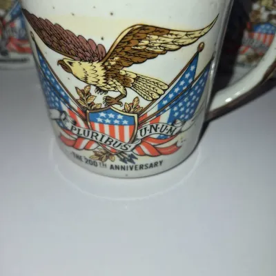 Sale Photo Thumbnail #580: Vintage 1976 United States Bicentennial ceramic mug featuring a bald eagle and E Pluribus Unum graphic with speckling detail.