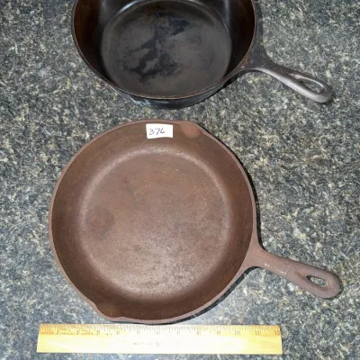Sale Photo Thumbnail #652: Two vintage cast iron pans displayed next to a ruler for scale, including a deep Dutch oven-style skillet and a shallow skillet showing surface rust.