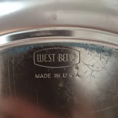 Sale Photo Thumbnail #814: Vintage West Bend stainless steel cookware piece showing maker's mark stamped on the bottom, with visible surface scratches and wear.