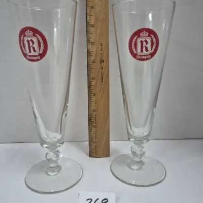 Sale Photo Thumbnail #456: Pair of vintage Rheingold beer pilsner glasses featuring the red crown logo, each measuring approximately nine and a half inches tall.
