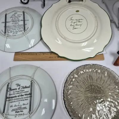 Sale Photo Thumbnail #410: Selection of decorative plates including a Danbury Mint "Flowers of Holland" collector plate, a W.S. George 1991 collector plate with wire hangers, a handwritten ceramic plate, and a clear textured glass platter.