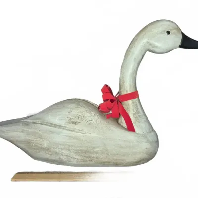 Sale Photo Thumbnail #538: Hand-carved painted wooden swan decoy with a black beak and decorative red bow tied around its neck.