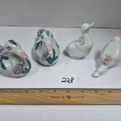 Sale Photo Thumbnail #392: Set of four vintage porcelain duck figurines, including two hand-painted with pink floral motifs and two white ducks adorned with applied ceramic flowers.