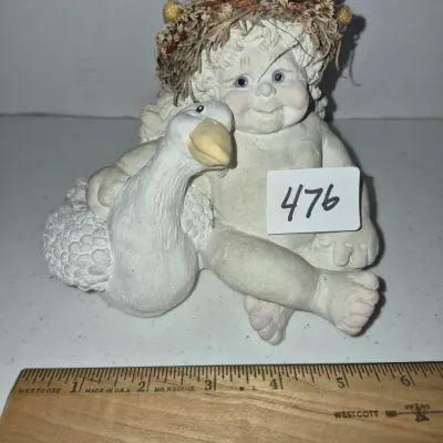 Sale Photo Thumbnail #818: Vintage resin or chalkware figurine of a cherub-like child hugging a goose with a dried flower wreath crown, measuring approximately 5 inches tall.