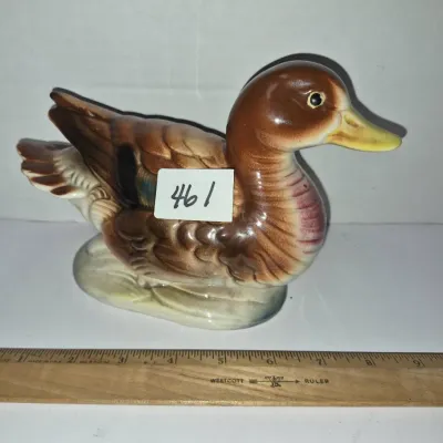 Sale Photo Thumbnail #796: Vintage glazed ceramic duck figurine in shades of brown, yellow, and blue, measuring approximately six inches long.