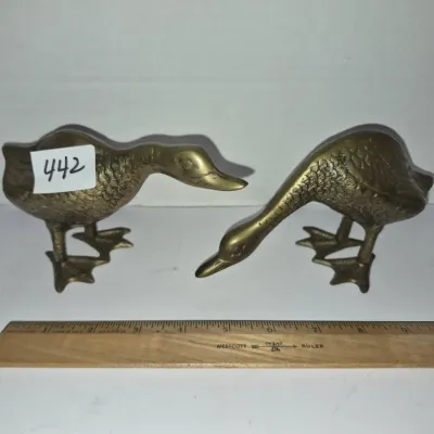 Sale Photo Thumbnail #767: Pair of vintage brass duck figurines with textured feather details, shown next to a wooden ruler for scale.