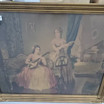 Sale Photo Thumbnail #530: Large vintage framed art print depicting two women making music in a classical parlor setting, housed in an ornate gilded wood frame measuring approximately 33 by 28 inches.