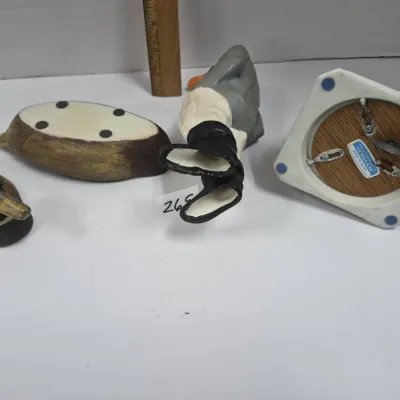Sale Photo Thumbnail #452: Group of vintage ceramic decorative items, including a mallard duck figurine, a Gorham wind-up music box base made in Japan, and a character figurine lying on its side.