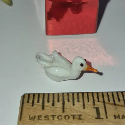 Sale Photo Thumbnail #235: Miniature white lampwork glass duck figurine measuring under one inch long.