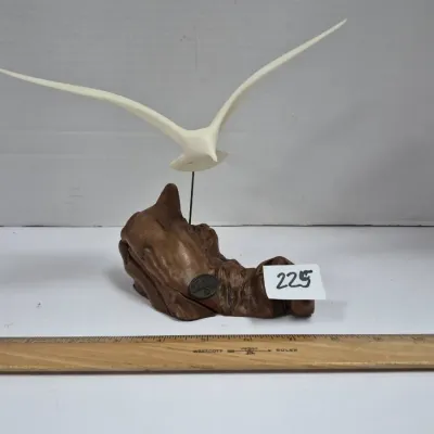 Sale Photo Thumbnail #387: Sculptural bird figurine depicting a bird in flight, mounted on a natural burl wood or resin base with a metal support rod.