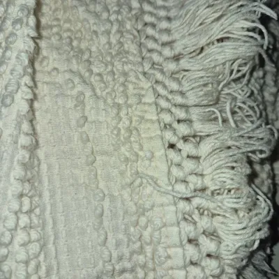 Sale Photo Thumbnail #86: Close-up view of a cream vintage candlewick chenille bedspread featuring fringed edging and textured raised cotton tufting.