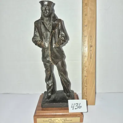 Sale Photo Thumbnail #758: Commemorative statue of "The Lone Sailor" from the United States Navy Memorial in Washington, D.C., set on a wooden base with a plaque and measuring approximately 10.5 inches tall.