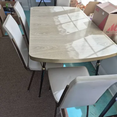 Sale Photo Thumbnail #840: Vintage mid-century Formica top dining table with four matching white vinyl upholstered chairs, featuring tapered metal legs with brass accents.