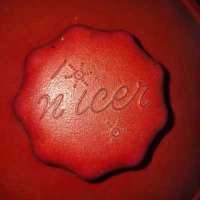 Sale Photo Thumbnail #562: Vintage red plastic ice bucket lid or kitchenware cover featuring a scalloped knob embossed with the brand name 'Nicer' and starburst motifs.