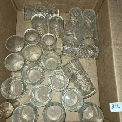 Sale Photo Thumbnail #547: Cardboard box packed with an assortment of clear vintage glassware, including highball glasses and cut glass tumblers.
