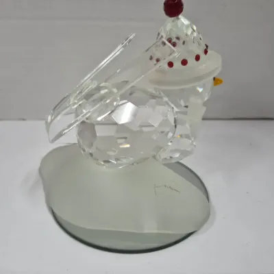 Sale Photo Thumbnail #414: Swarovski crystal figurine depicting a snowman with skis on a frosted glass base, featuring red and yellow accents.