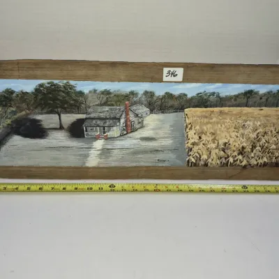 Sale Photo Thumbnail #604: Rustic folk art landscape painting on a reclaimed wood board, depicting a rural farmhouse adjacent to a field. Measures approximately 28 inches long.