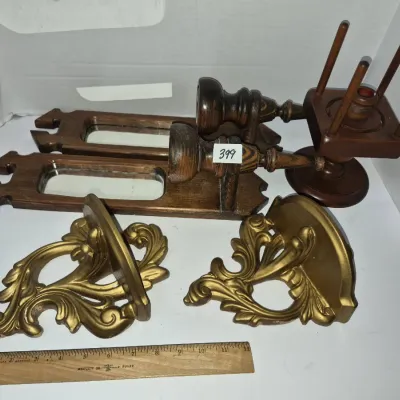 Sale Photo Thumbnail #702: Collection of vintage home decor items, including a pair of dark wood mirrored sconces, a wooden candle holder stand, and a pair of gold-painted ornate wall shelves.
