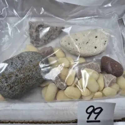 Sale Photo Thumbnail #155: Collection of assorted rocks, stones, and small smooth pebbles stored inside a clear plastic bag, with one rock bearing handwritten gold text.