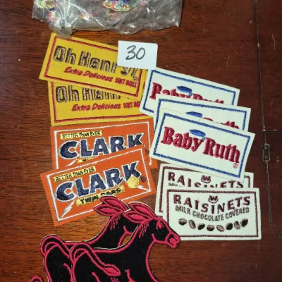 Sale Photo Thumbnail #47: Collection of vintage embroidered sew-on patches featuring candy advertising logos like Oh Henry!, Clark, Baby Ruth, Raisinets, and animal shapes.