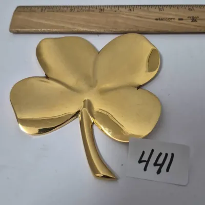 Sale Photo Thumbnail #765: Polished solid brass four-leaf clover trivet or paperweight, measuring approximately 5 inches wide.
