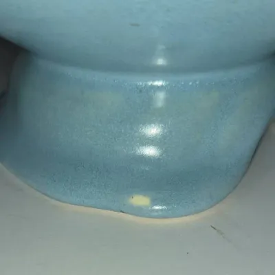 Sale Photo Thumbnail #267: Close-up detail of a light blue glazed ceramic piece, highlighting a small glaze chip on the lower edge.