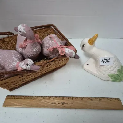 Sale Photo Thumbnail #816: Collection of country-style goose decor, including three painted pink ceramic ducks in a straw-lined basket and a white glazed ceramic goose wall hook.