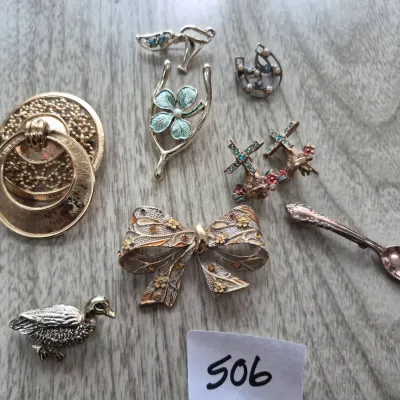 Sale Photo Thumbnail #871: Collection of vintage costume jewelry brooches and pins, including a bow motif pin, a duck pin, a small spoon pin, and a wishbone with a four-leaf clover.
