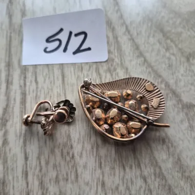 Sale Photo Thumbnail #884: Vintage gold-tone leaf-shaped brooch with inset stones alongside a matching screw-back earring, displayed next to a lot tag.