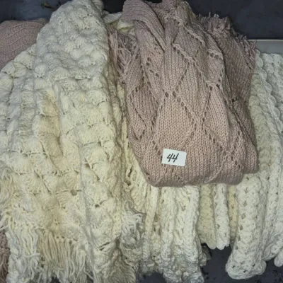Sale Photo Thumbnail #69: Collection of handmade knit and crochet blankets in cream and dusty rose tones, featuring varied textures and fringe details.