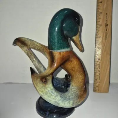 Sale Photo Thumbnail #279: Stylized mid-century modern ceramic mallard duck figurine featuring a glazed finish in teal, brown, and cream tones, standing approximately 7 inches tall.
